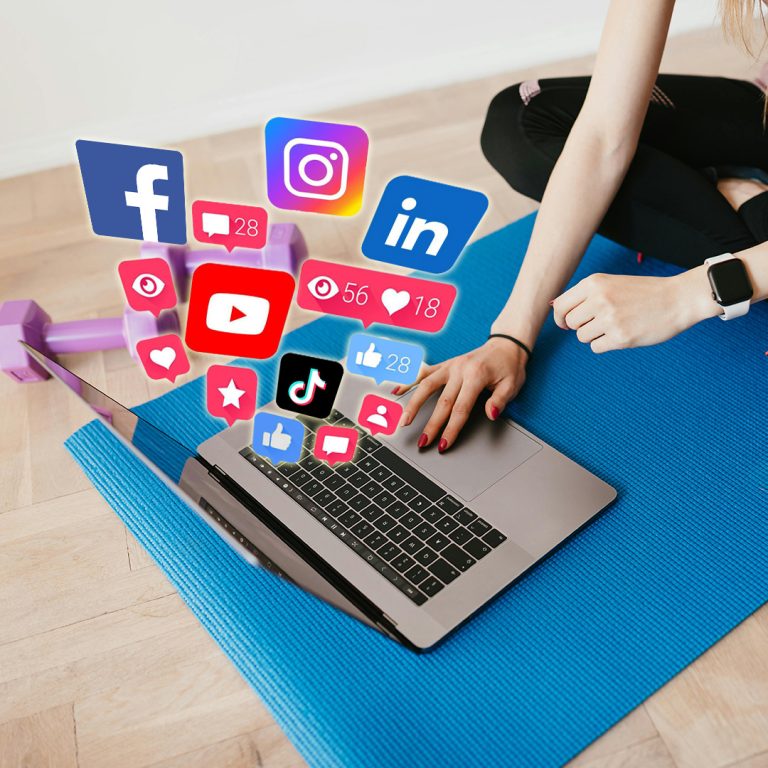 Fitness coach managing social media from laptop with floating icons of likes, messages, views, and hearts, symbolizing content engagement and online visibility.